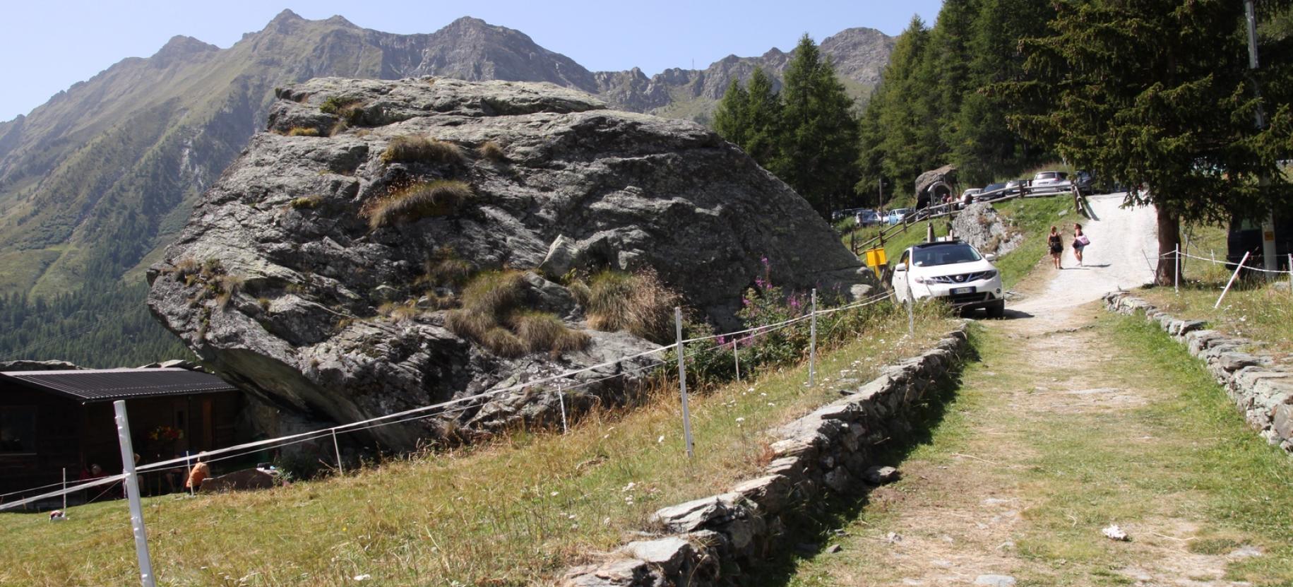 Il grande masso e la strada che sale al parcheggio.