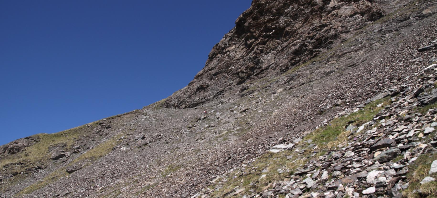 Salita su terreno detritico alla base della parete rocciosa.